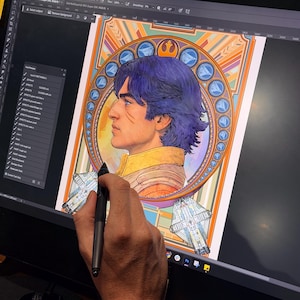May include: Digital artwork of a man with blue hair in profile, surrounded by a decorative circular frame with geometric and celestial elements. The artwork is being created on a digital drawing tablet, with a stylus in use.