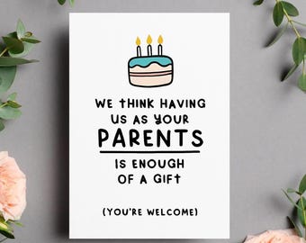 May include: A white greeting card with a cartoon cake illustration and the text "WE THINK HAVING US AS YOUR PARENTS IS ENOUGH OF A GIFT (YOU'RE WELCOME)". The card is surrounded by greenery and pink roses.