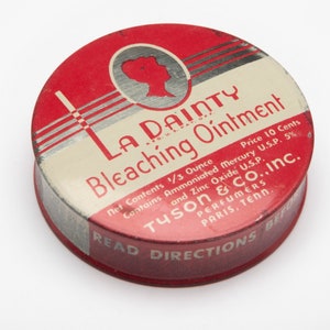May include: A red and white round tin container with the text "La Dainty Bleaching Ointment" and "Tyson & Co., Inc. Perfumer Paris, Tenn." The tin has a silver stripe design and a woman's face in a circle.
