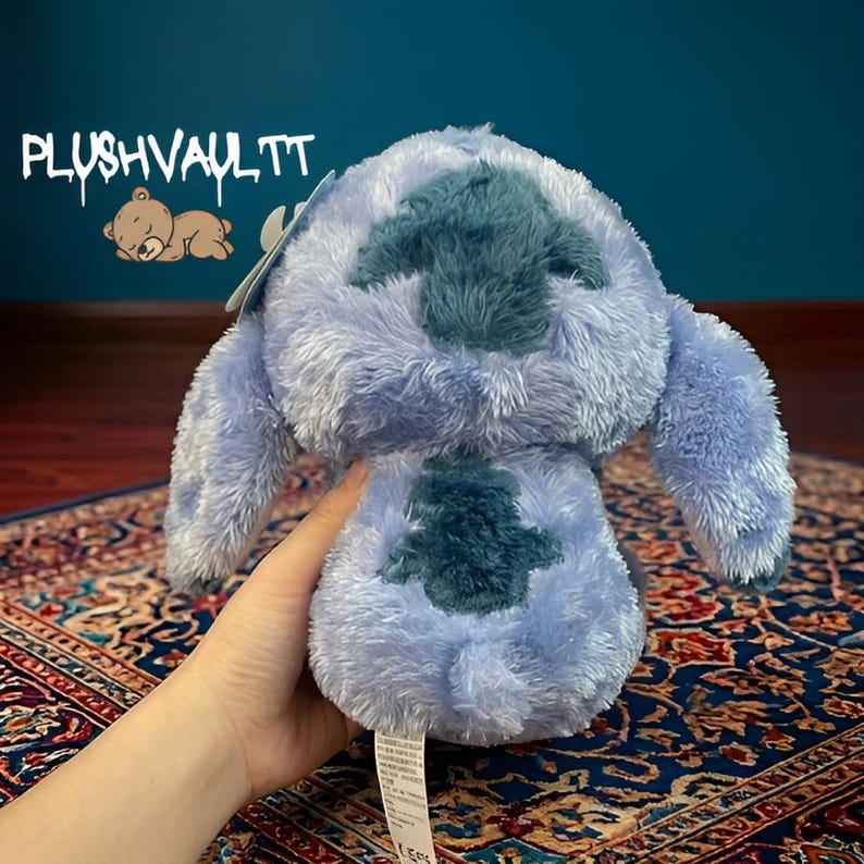 Soft blue alien plush with sparkly star eyes being held. A comforting Lilo and Stitch character gift for fans.