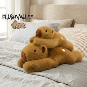 Puede incluir: Dos osos de peluche marrones sobre una cama. Uno está acostado y el otro encima, abrazándolo. Los osos tienen narices marrones oscuras y ojos negros pequeños. El texto "PLUSHVAULTT" está encima de los osos.