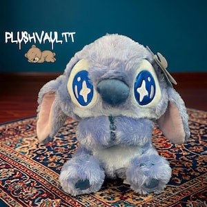 Soft blue alien plush with sparkly star eyes being held. A comforting Lilo and Stitch character gift for fans.
