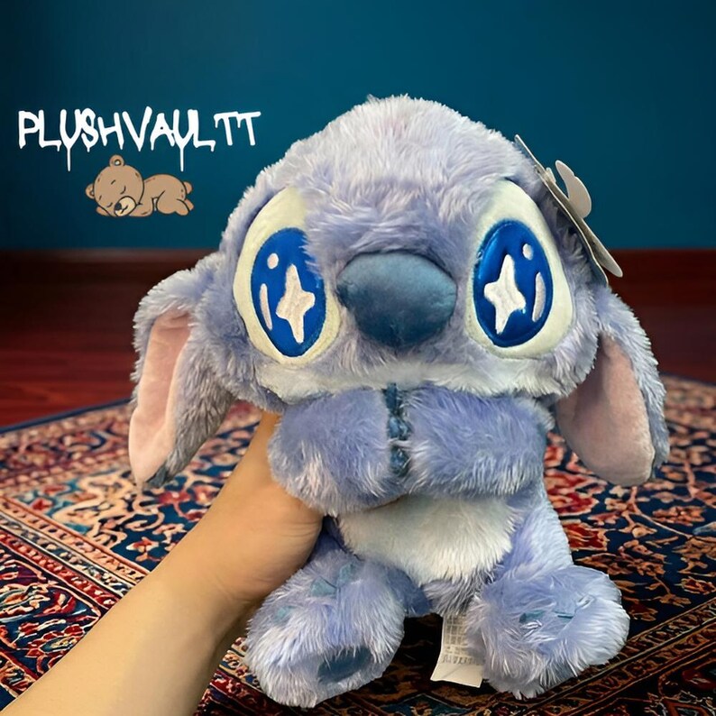 Soft blue alien plush with sparkly star eyes being held. A comforting Lilo and Stitch character gift for fans.