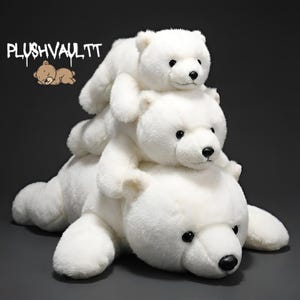 Puede incluir: Tres osos polares de peluche blancos apilados. El oso más grande está acostado, sosteniendo un oso de tamaño mediano, que a su vez sostiene un oso pequeño. Los osos tienen ojos y narices negras. El texto "PLUSHVAULT.TT" está en la esquina superior izquierda.