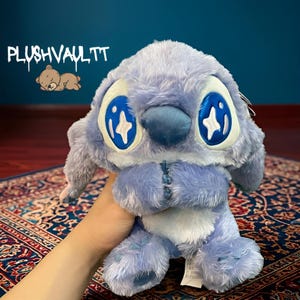 Soft blue alien plush with sparkly star eyes being held. A comforting Lilo and Stitch character gift for fans.
