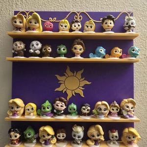 May include: A purple display shelf with three levels, holding a collection of small figurines. The figurines feature characters from a popular animated movie, with a gold sun design in the center.