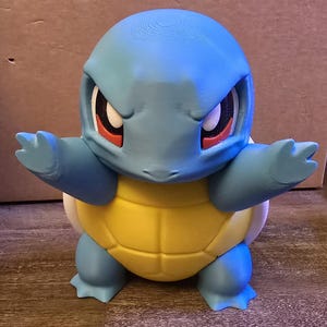 May include: A 3D-printed Squirtle figure, with a light blue head and limbs, a yellow shell, and white details. The figure has red and white eyes and is posed with arms outstretched.