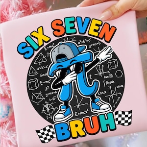 May include: Pink t-shirt with a graphic featuring a blue Pi symbol wearing sunglasses and a hat, dabbing. The design includes mathematical equations and the word "BRUH" with checkered flags.