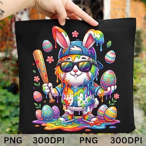 Puede incluir: Bolso tote negro con un diseño de conejo de Pascua de dibujos animados colorido. El conejo lleva gafas de sol, una gorra de béisbol y zapatillas, sosteniendo un bate y un huevo de Pascua. El diseño incluye colores arcoíris y huevos de Pascua.