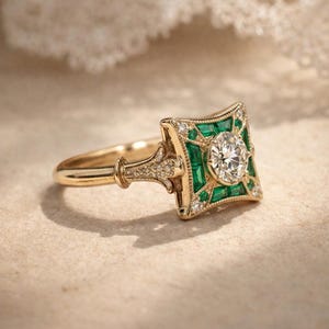 May include: A gold ring with a square emerald and diamond design. The center features a round diamond, surrounded by emeralds and smaller diamonds. The ring has a detailed band and a vintage aesthetic.