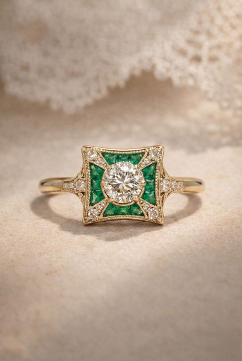 May include: A gold ring featuring a central round diamond, surrounded by emeralds and smaller diamonds in a square design. The ring has a vintage, art deco style with intricate detailing.