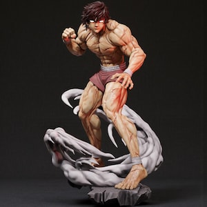 May include: A detailed figurine of a muscular male figure in a fighting stance. The figure has brown hair, red eyes, and is wearing maroon shorts and wristbands. It stands on a gray, cloud-like base with a rocky texture.