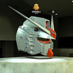 Puede incluir: Una detallada cabeza de robot gris metálico con detalles en rojo, que presenta una larga antena y un diseño angular. La cabeza está renderizada en 3D y parece flotar. El texto "PATNULL 3D STL" es visible.