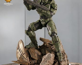 May include: A green action figure of a soldier in combat armor, holding a rifle. The figure is posed on a rocky base with a futuristic design element. The figure is wearing a helmet with a gold visor. The logo "PATNULL 3D STL" is visible.