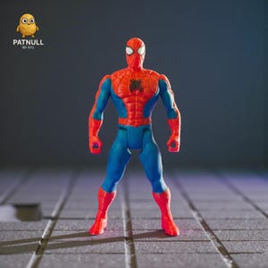 May include: A red, blue, and black Spider-Man action figure. The figure is standing on a gray surface. The figure has a red torso and legs, blue arms and legs, and a black spider emblem on the chest. The figure's eyes are white.