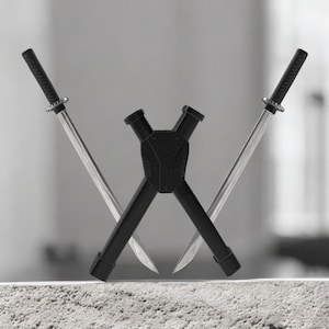 May include: Two silver katanas crossed with black handles and a black stand. The blades are sharp and the handles are textured. The stand is also black and has a unique design.
