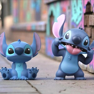 K&ouml;nnte beinhalten: Zwei blaue Stitch-Figuren. Eine sitzt mit ausgestreckten Pfoten, die andere steht und zieht an ihren Ohren. Die Figuren haben gro&szlig;e Augen und rosa Innenohren. Der Hintergrund ist eine verschwommene Stra&szlig;enszene.
