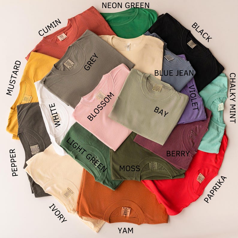 May include: A collection of folded t-shirts in various colors, including mustard, pepper, cumin, white, ivory, grey, blossom, light green, neon green, moss, yam, blue jean, bay, berry, violet, black, paprika, and chalky mint. Each shirt has a tag.