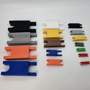 Peut inclure: Une collection de jauges d'&eacute;cartement pour roues de trains miniatures en plastique multicolore de diff&eacute;rentes tailles. Les jauges portent des mesures sp&eacute;cifiques en millim&egrave;tres et pouces, incluant G Gauge, Gauge-1, S Scale et EM B2B Gauge.