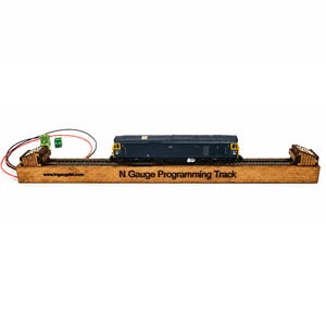May include: A wooden N Gauge Programming Track base with a blue and yellow model diesel locomotive resting on the rails. The base features the text N Gauge Programming Track and a website URL, with two green electrical connectors and red and black wires.
