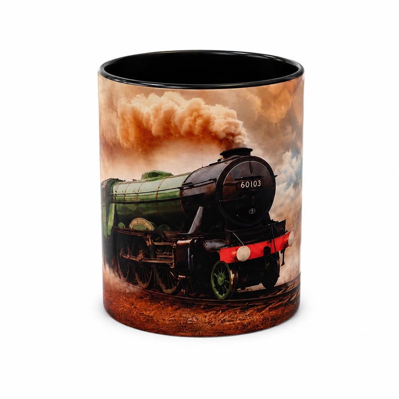 Może przedstawiać: Cylindryczny ceramiczny kubek z czarnym wnętrzem i krawędzią, ozdobiony szczeg&oacute;łową grafiką parowozu Flying Scotsman o numerze 60103 w kolorze zielonym i czarnym, na tle dramatycznego zachmurzonego nieba i brązowego podłoża.