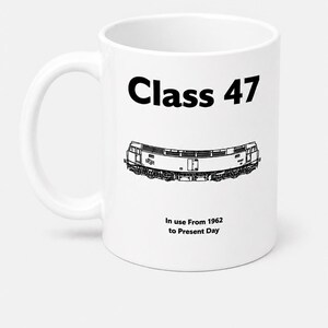 May include: A white ceramic mug featuring a black graphic illustration of a Class 47 locomotive. The text "Class 47" appears in bold black letters above the train, with the text "In use From 1962 to Present Day" printed in black below the train.