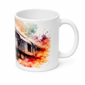 Peut inclure: Un mug en c&eacute;ramique blanche orn&eacute; d'une illustration de train style aquarelle. Le motif repr&eacute;sente une voiture de train dans des tons de bleu et de gris, entour&eacute;e d'&eacute;claboussures de peinture abstraites et vives orange, rouge, jaune et bleu sarcelle.