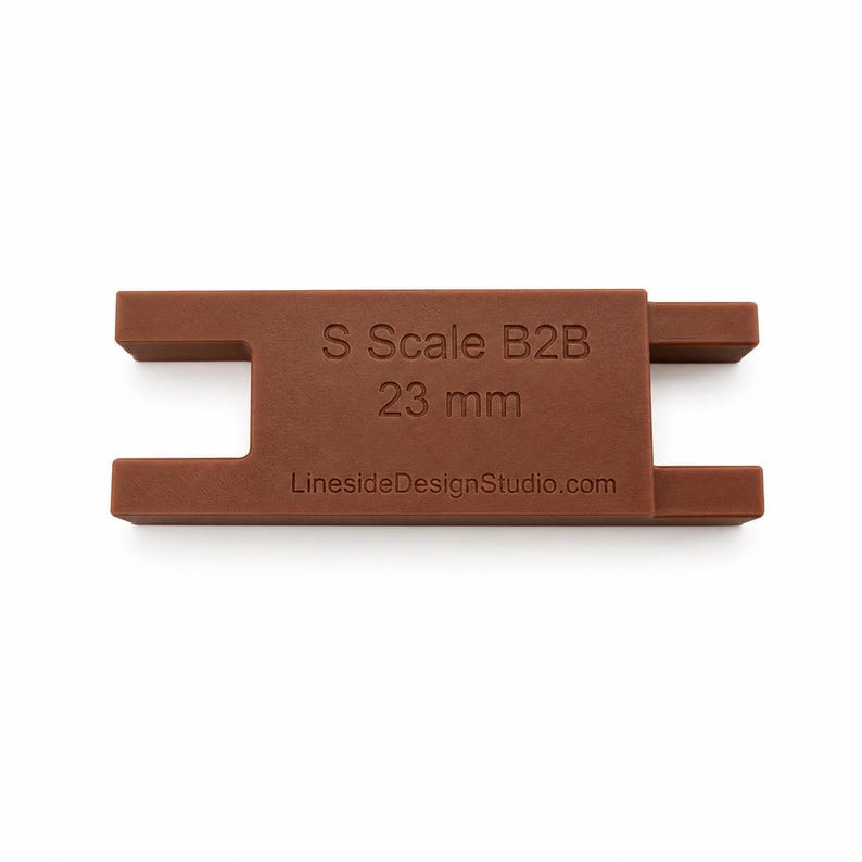 Peut inclure: Un outil de mesure S Scale B2B 23 mm marron avec un corps rectangulaire et deux d&eacute;coupes en forme de U sur les c&ocirc;t&eacute;s. Le texte S Scale B2B 23 mm et LinesideDesignStudio.com est grav&eacute; sur la face avant de cet outil de mod&eacute;lisme ferroviaire.