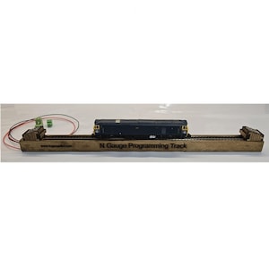 Op de afbeelding: Een houten N Gauge Programmeerspoor met een donkerblauwe modeltrein. Het spoor heeft de tekst "N Gauge Programming Track" en het websiteadres "www.lngaugekit.com". Ontworpen voor modeltrein-enthousiastelingen.