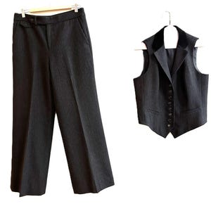 Peut inclure: Un ensemble gilet et pantalon gris anthracite à fines rayures. Le gilet présente un col en velours noir, une fermeture boutonnée et deux poches avant. Le pantalon est doté d'une coupe droite, d'une ceinture à passants et de poches latérales.