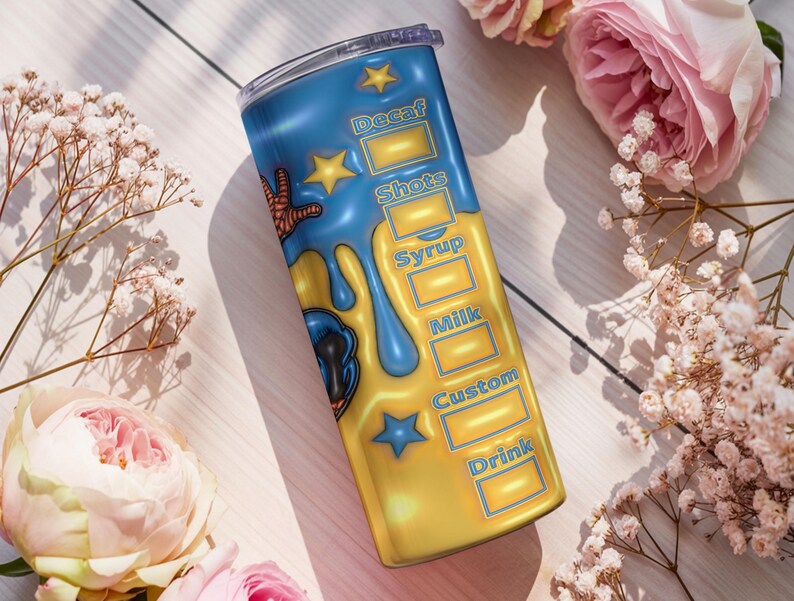 May include: A blue and yellow insulated tumbler with a cartoon design and the words "Decaf", "Shots", "Syrup", "Milk", "Custom", and "Drink". The tumbler has a clear lid and is decorated with stars and a cartoon character. The background includes flowers.