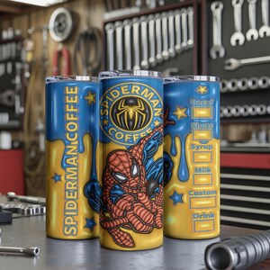 May include: Three stainless steel tumblers with a blue and yellow design featuring Spider-Man. One tumbler reads "Spider-Man Coffee" and another has a coffee drink recipe. The tumblers are on a metal surface in a workshop.