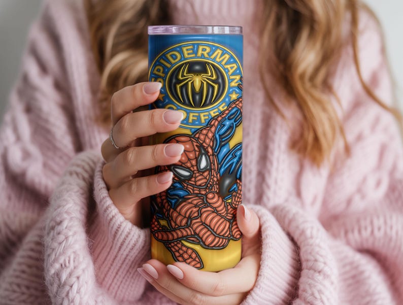 May include: A tall, cylindrical tumbler with a Spider-Man design. The tumbler has a blue background with the words "Spider-Man Coffee" and a Spider-Man logo. The superhero is shown in his classic red and blue suit.