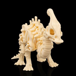 Puede incluir: Modelo de esqueleto de dinosaurio Parasaurolophus de color crema. El modelo presenta una estructura ósea detallada, incluyendo una cresta distintiva y extremidades articuladas. El dinosaurio está posado a cuatro patas sobre un fondo negro.