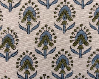 May include: Close-up of a fabric with a repeating floral pattern. The design features stylized flowers in shades of blue and olive green against a cream-colored background. The fabric has a textured appearance.