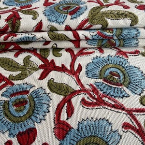 May include: A woven fabric featuring a repeating floral pattern on an off-white background. The design consists of light blue flowers with olive green centers, connected by deep red stems and olive green leaves, creating a dense botanical motif.