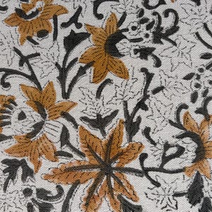 Könnte beinhalten: Nahaufnahme eines Stoffes mit einem sich wiederholenden Blumenmuster. Das Design zeigt stilisierte Blumen in Gold- und Schwarztönen auf weißem Hintergrund. Das Muster umfasst Blätter und Ranken.