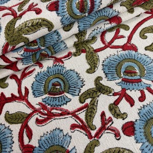 May include: A woven fabric featuring a repeating floral pattern on an off-white background. The design consists of light blue stylized flowers with olive green leaves and thin red stems, creating a dense, textured botanical print across the surface.