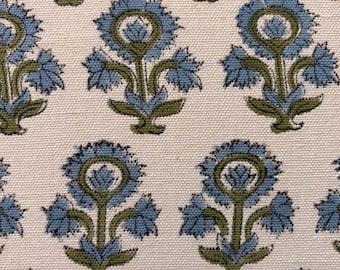 May include: Close-up of a fabric with a repeating floral pattern. The flowers are blue with green stems and leaves, set against a cream-colored background. The design is symmetrical and detailed.