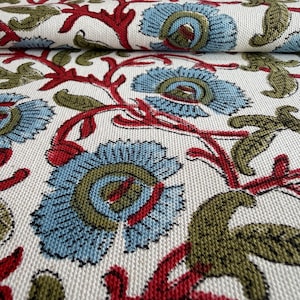 May include: A woven fabric featuring a repeating floral pattern on an off-white background. The design consists of light blue flowers with olive green centers, connected by vibrant red stems and accented with olive green leaves throughout.