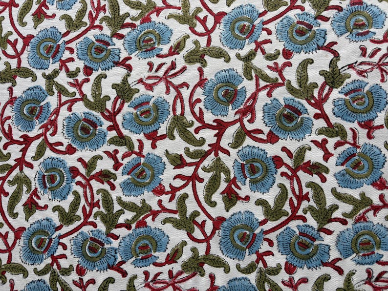 May include: A textile fabric featuring a repeating floral pattern on a white background. The design consists of light blue flowers with dark red centers, connected by winding dark red stems and olive green leaves throughout the surface.