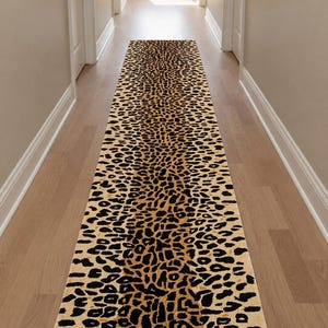 Könnte beinhalten: Ein langer, rechteckiger Läufer mit einem sich wiederholenden Leopardenmuster in Beige-, Braun- und Schwarztönen. Der Teppich hat eine dichte Kurzflor-Struktur und erstreckt sich in einer geraden Linie über den Boden mit einem einheitlichen Tiermotiv.