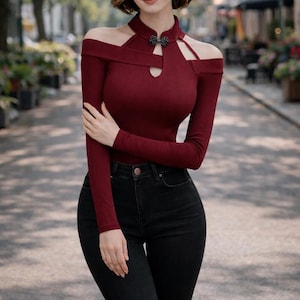 Könnte beinhalten: Ein weinrotes Langarm-Top mit Off-Shoulder-Design und Schlüsselloch-Ausschnitt. Das Top wird mit einer schwarzen Jeans kombiniert. Das Top hat eine dekorative Verzierung am Ausschnitt. Das Outfit eignet sich für einen lässigen oder halbformellen Anlass.