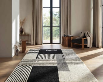 May include: A rectangular area rug featuring a geometric pattern of black, white, and gray blocks and stripes. The design includes solid black sections, white textured areas, and striped panels. The text Weavers Pointt is visible.
