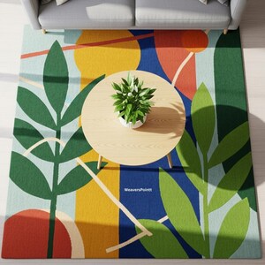 以下が含まれることがあります： モダンな抽象デザインのカラフルなラグ。大きな緑の葉の形、黄色とオレンジの円、青と水色の背景が特徴です。丸い木製のコーヒーテーブルには鉢植えの植物が置かれています。