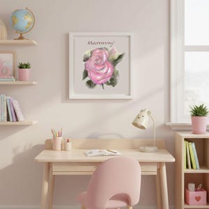 Può includere: Una stampa incorniciata con un'illustrazione di rosa rosa con la parola "Mammy" sopra il fiore. L'opera d'arte è in una cornice bianca e appesa a una parete rosa chiaro. La stanza comprende una scrivania, una sedia e delle mensole.