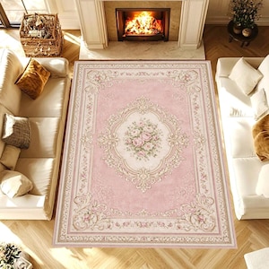 Può includere: Un tappeto rettangolare rosa con un design floreale ornato. Il tappeto presenta un medaglione centrale con un bouquet di rose rosa e un bordo color crema. Il tappeto è circondato da un bordo dettagliato con motivi floreali e a volute.