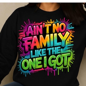Peut inclure: Sweat-shirt noir avec l'inscription "AIN'T NO FAMILY LIKE THE ONE I GOT" dans un style graffiti coloré. Le texte est bordé de noir et présente un dégradé arc-en-ciel.