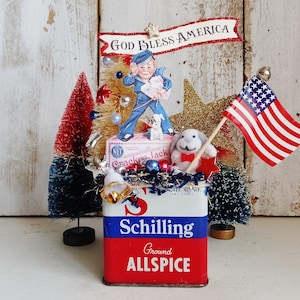 May include: A decorative display featuring a vintage Schilling Ground Allspice tin as a base, topped with a Cracker Jack box, a sailor figure, a small plush rabbit, a miniature American flag, and bottle brush trees in red, white, and blue.