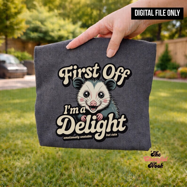 May include: Dark gray t-shirt featuring a cartoon opossum with the text "First Off I'm a Delight" and "emotionally unstable but cute". The image is a digital file.